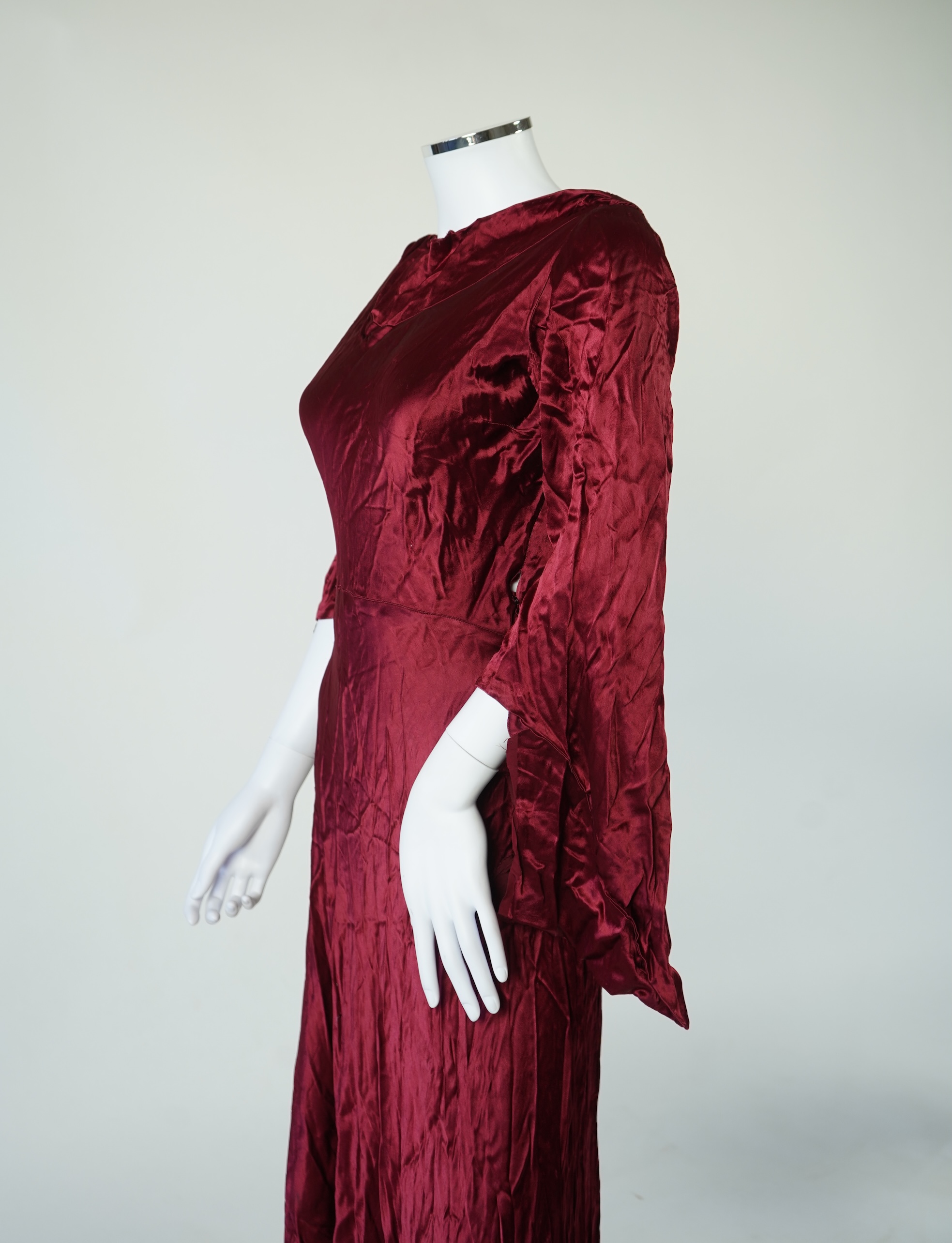 A 1920’s light green silk evening cape with hand batik borders and label: Tito de Canival Mode, together with a navy ladies two piece suit and a maroon satin evening dress. Cape 100cm long. Condition - cape good, navy tw